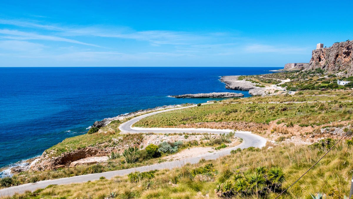 Panoramic road to drive over the Mediterranean sea. Wild coastline with rocks and sandy beaches, against a deep blue sea at San Vito Lo Capo, Palermo, Sicily.